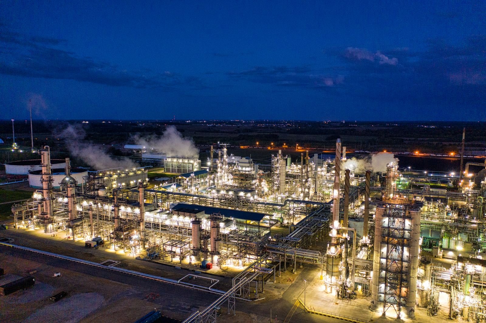 A process plant lit at night, pipework and columns picked out against the dark.