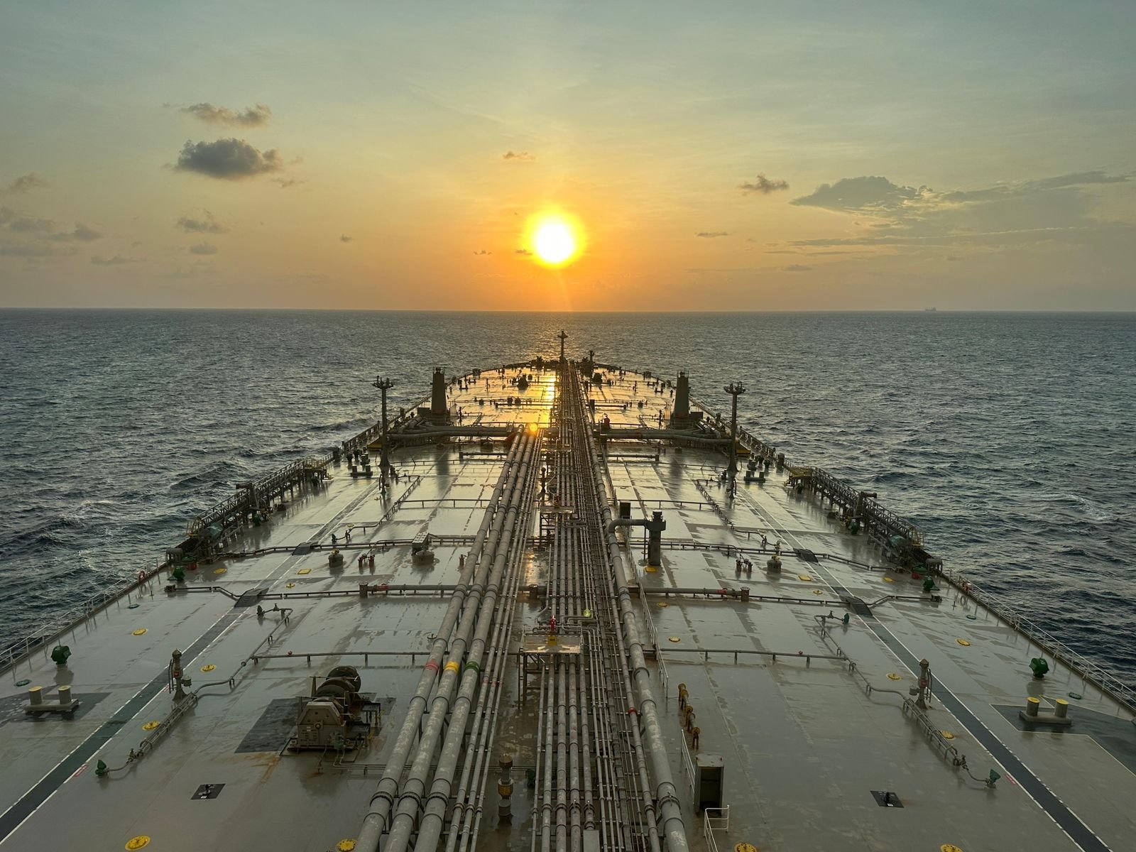 A laden oil tanker under way on open water at dusk.