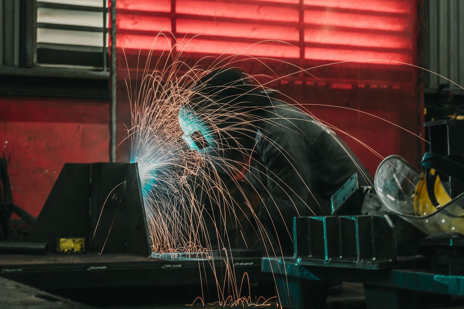 A welder joining steel sections during fabrication work.